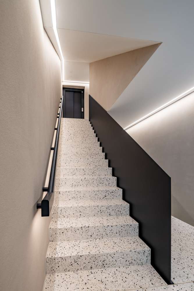 Treppenhaus: Terrazzo, Brüstung aus schwarzem Stahlblech, Lichtlinien in den Wandkanten.