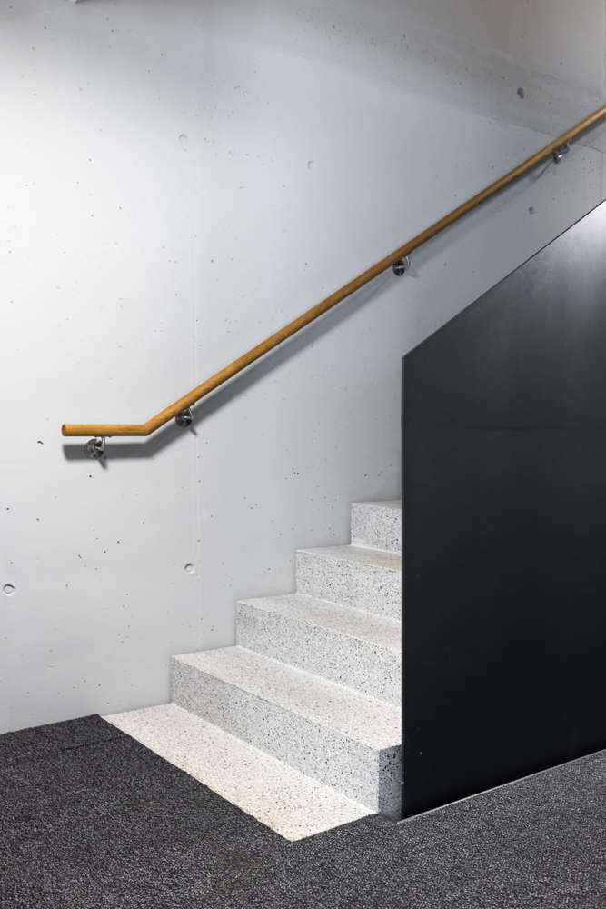 Treppenlauf im Detail: Der Eichenhandlauf ist auf Edelstahlkonsolen an die Sichtbetonwand gesetzt.