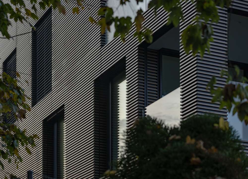 Fassadendetail: Die Profile sind auf ein schwarz beschichtetes Grundblech geklipst; das Eloxal ergibt keinen Farbton, sondern einen Verlauf nach Licht und Sonnenstand.
