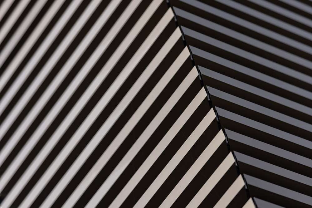 Fassadendetail an der Gebäudeecke: Die horizontalen Aluminiumprofile laufen über die Ecke, das schwarze Grundblech dahinter gibt der Hülle Tiefe; das Eloxal wechselt mit dem Licht zwischen Hell und Dunkel.