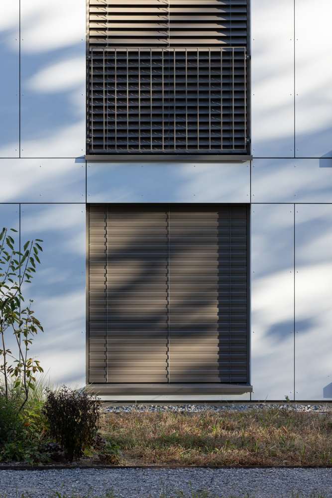 Fensterdetail: Rafflamellenstore, Absturzsicherung als Gitter und Fensterbank in einem Ton, die Platten mit sichtbarer Verschraubung.