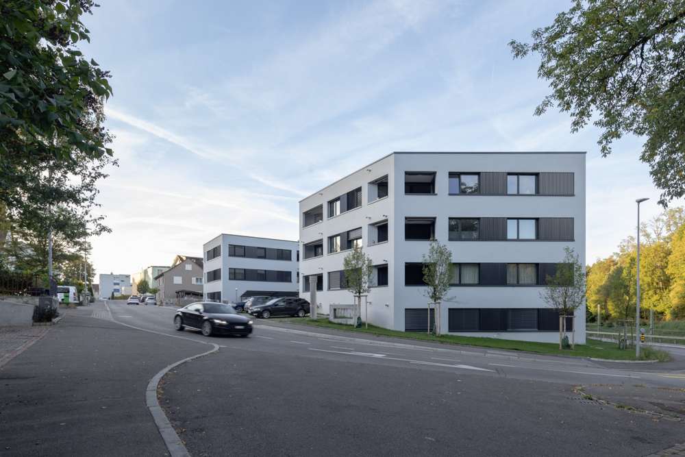 Die Anlage von der Engestrasse her gesehen: Die Baukörper folgen dem Strassenverlauf, die Loggien sind in die verputzte Fassade eingeschnitten, dazwischen liegen Fensterbänder mit dunklen Metallpaneelen.