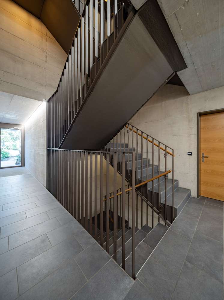 Eingangshalle: Sichtbeton, Stahltreppe mit Stabgeländer, Holzhandlauf, Blick in den Garten.